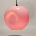 Hängeleuchte aus korallenrosa Glas mit glänzendem Finish, vor neutralem Hintergrund