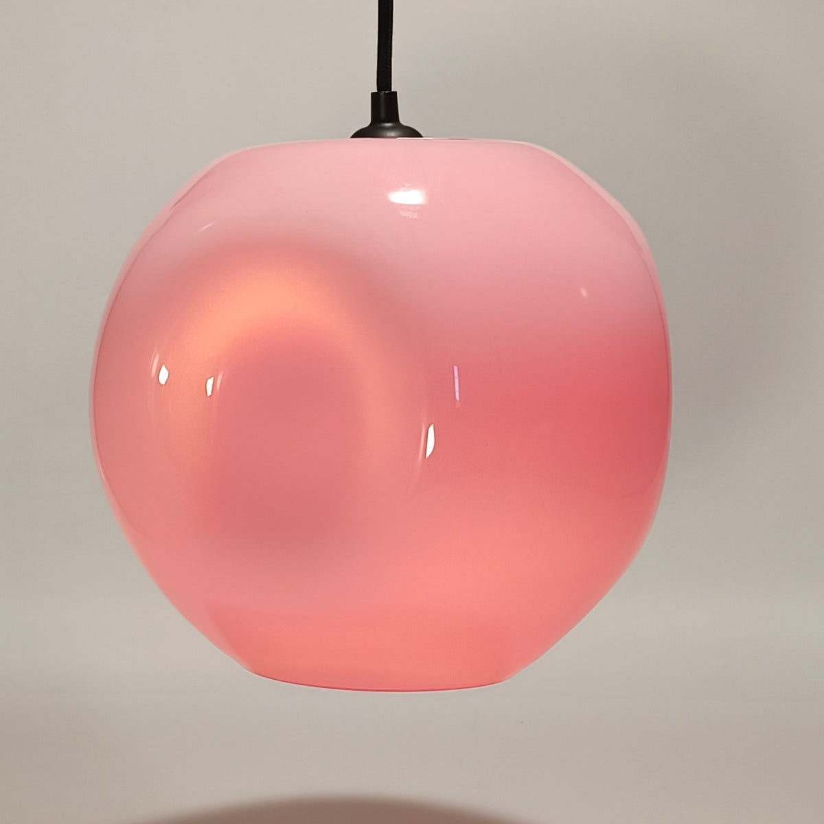 Hanglamp van koraalroze glas met glanzende afwerking, op een neutrale achtergrond