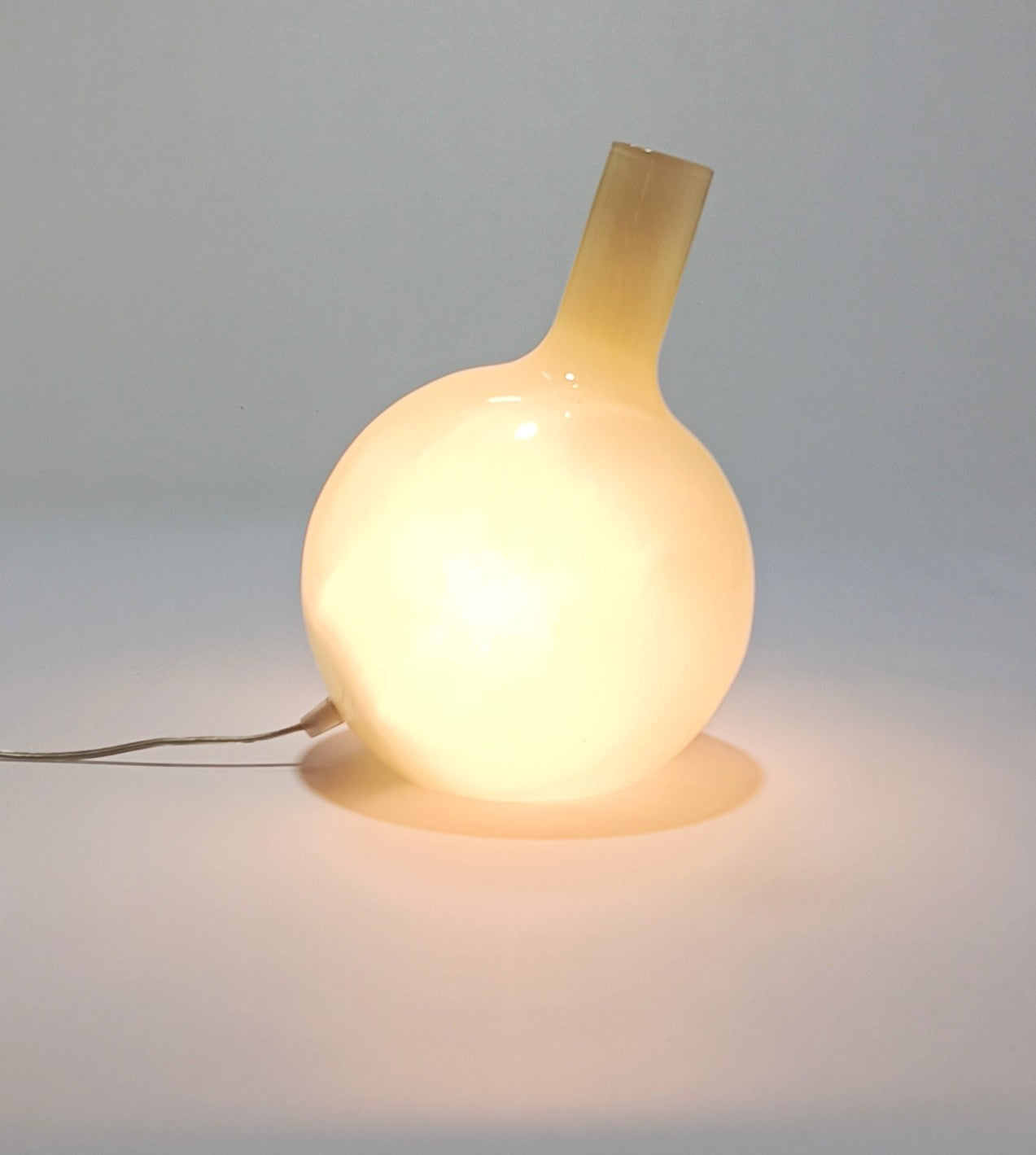 Candeeiro Halo Brando aceso, emitindo luz difusa e quente através do vidro opalino.