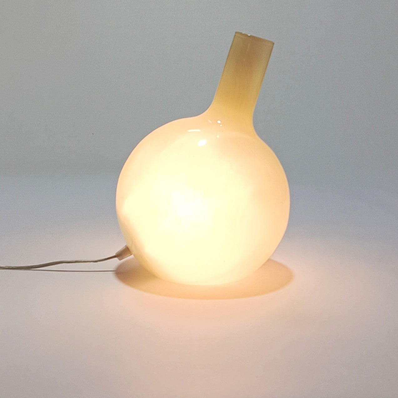 Candeeiro Halo Brando aceso, emitindo luz difusa e quente através do vidro opalino.