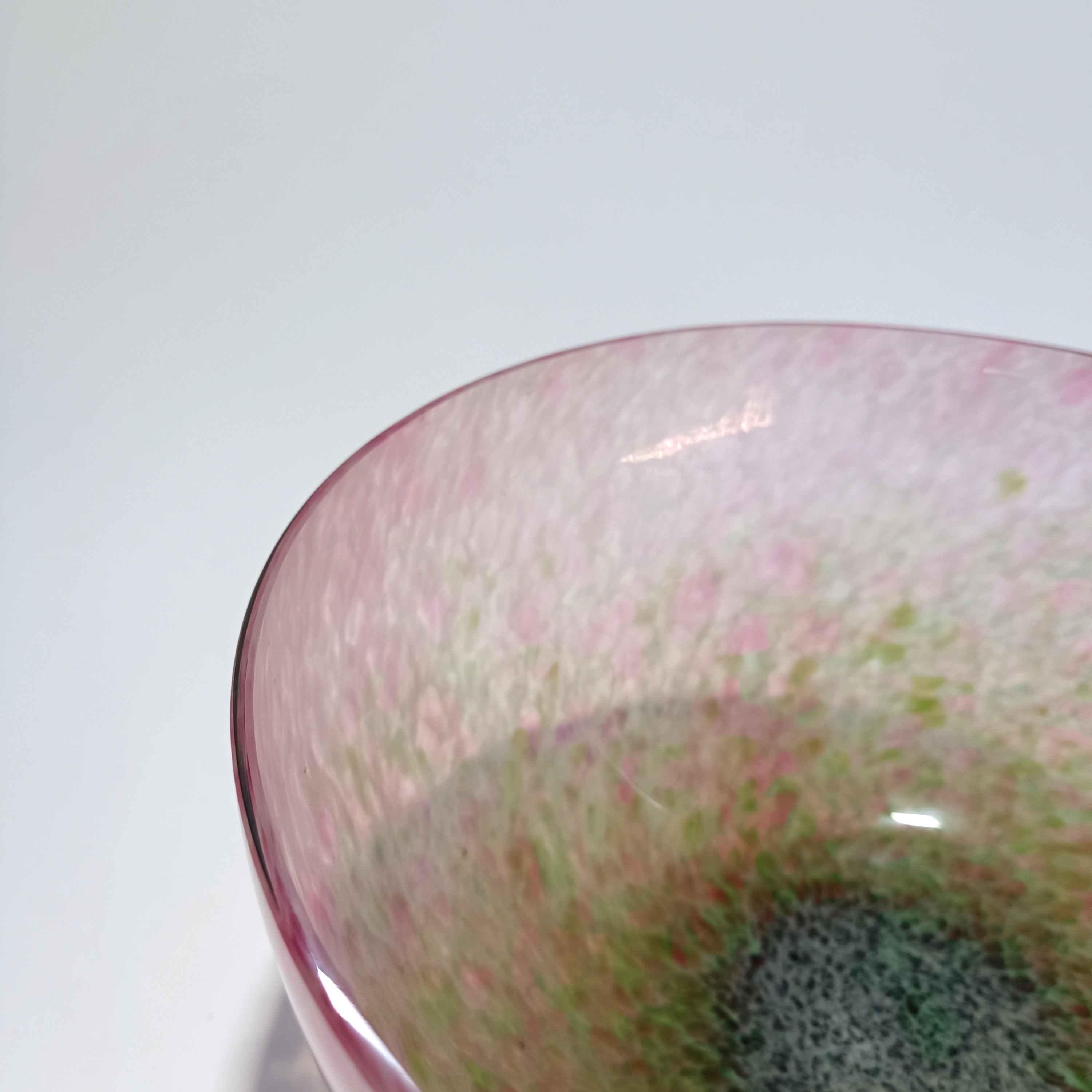 Artistic blown glass bowl in pink and green tones with textured pattern