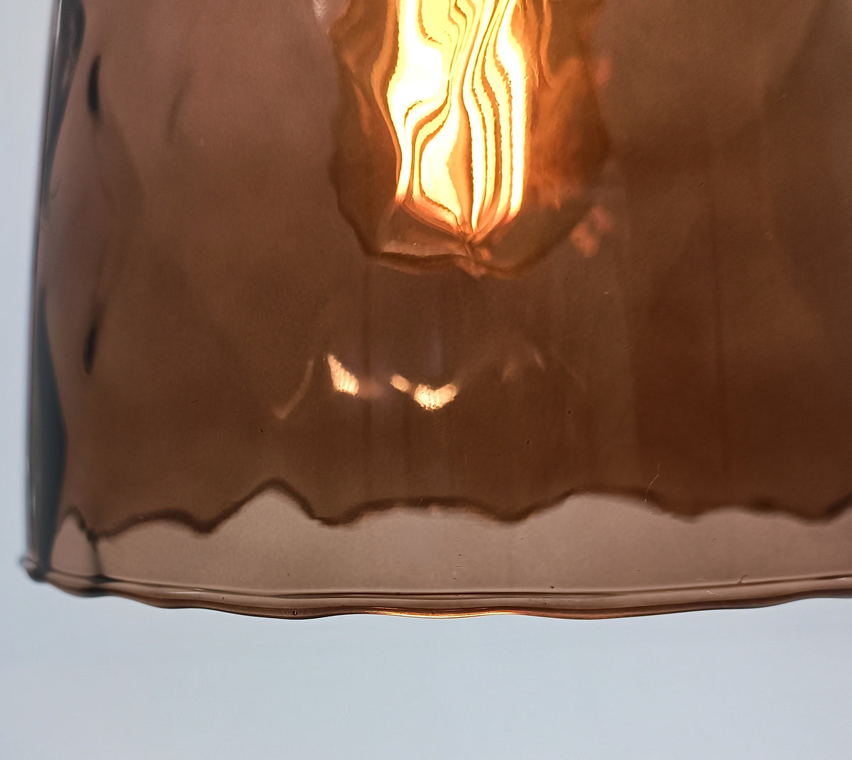 Hammered texture and wavy rim of the wine-brown blown glass on the DÔMEA pendant light