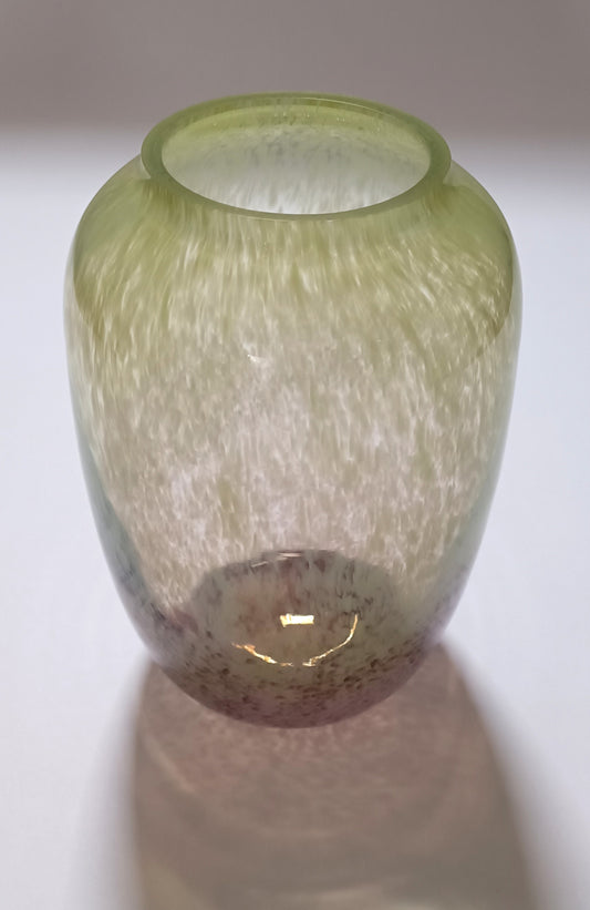 Vaso em vidro verde e rosa visto ligeiramente de cima, mostrando a boca arredondada e o interior translúcido.